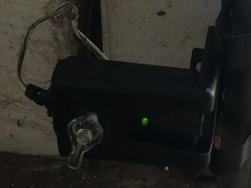 Garage door safety sensor mounted near the floor with its green light on